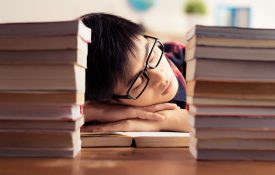 Student sleeping between piles of books