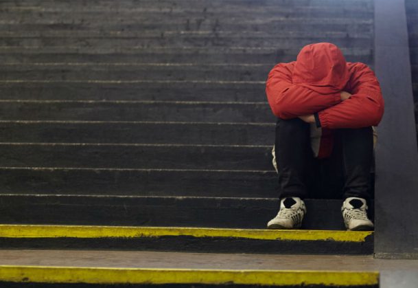 This is a photo of a teen sitting alone on a set of stairs.