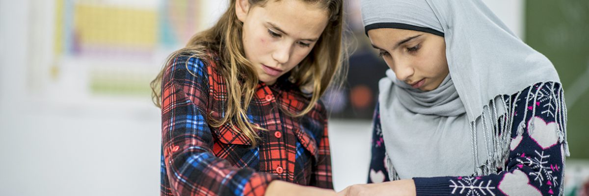 Two girls working together with wires and circuits during science class.