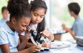 Two young girls looking into a microscope.