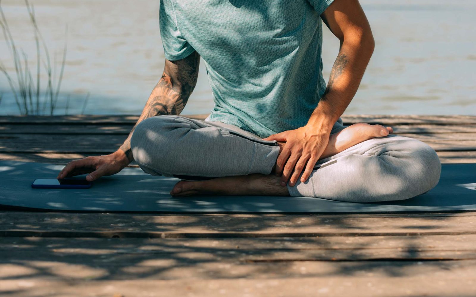 Man sitting on yoga mat and using phone.