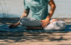 Man sitting on yoga mat and using phone.