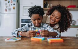 A mother and child play with toys on a kitchen counter.