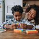 A mother and child play with toys on a kitchen counter.