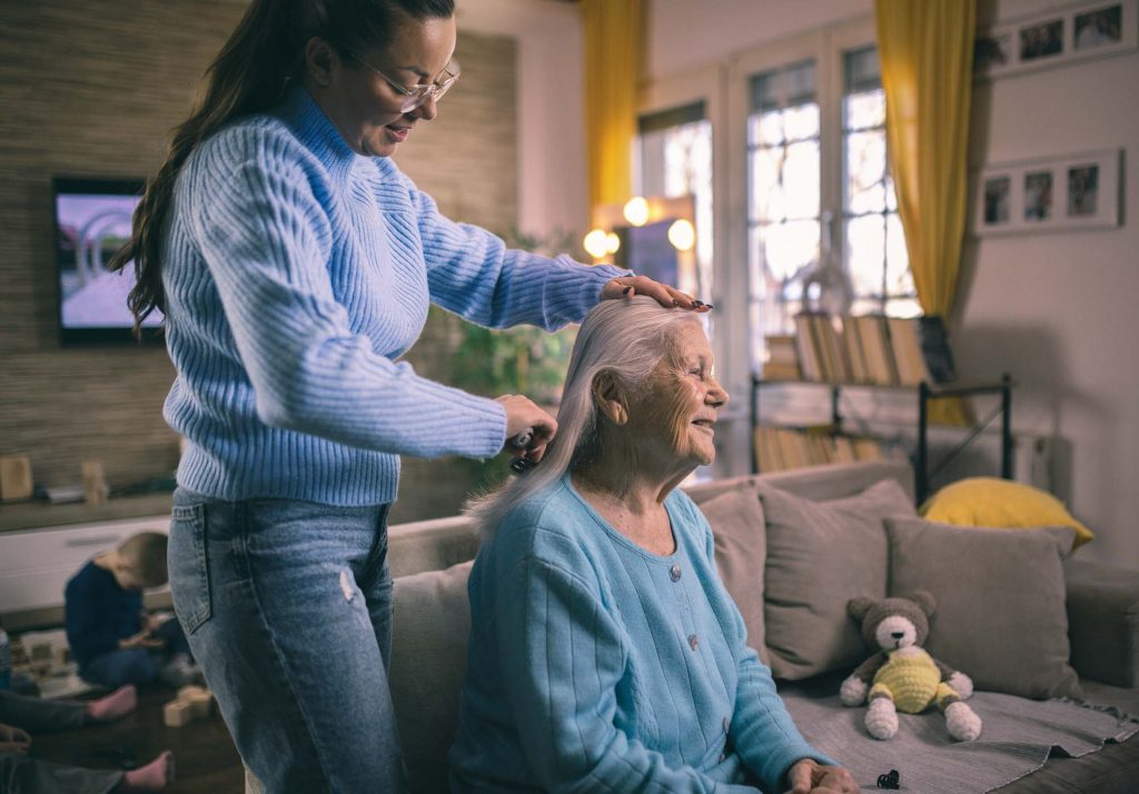 A younger woman brushes the hair of an older woman.