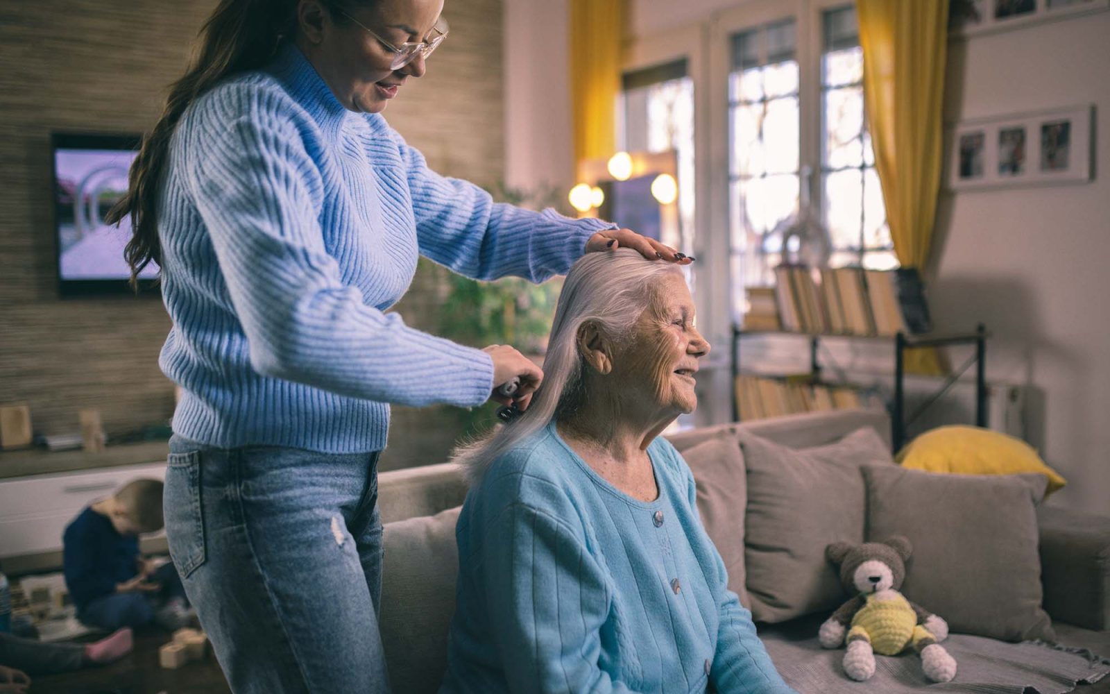 A younger woman brushes the hair of an older woman.