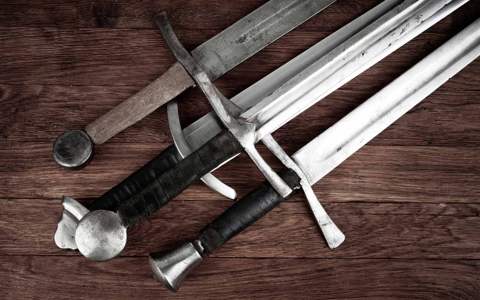 Four swords on a wooden background.